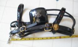 Pretty little harness. New and unused but has been laying around awhile. The brass could use some polish. There is an over-check but I removed it. It can easily be refitted if you want to use it. The head stall and saddle are black patent leather with
